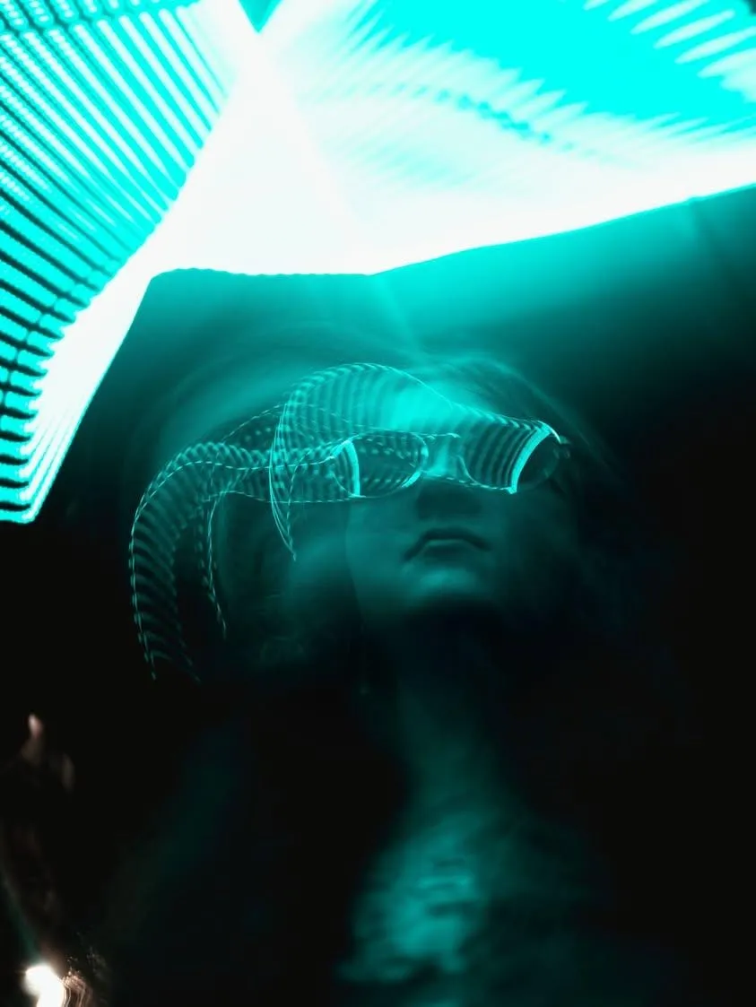 Figure moving through cyan light trails in a dark space