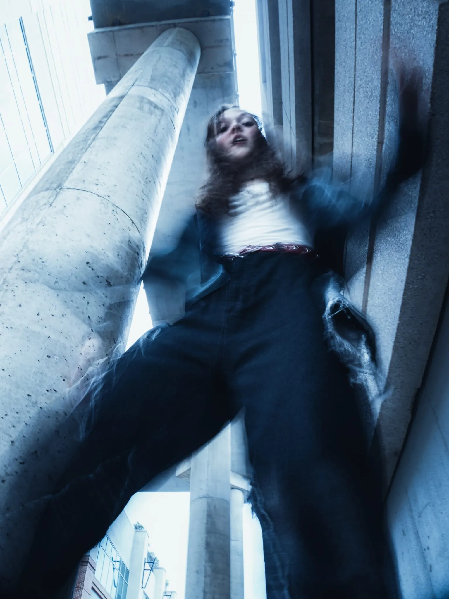 Low-angle editorial portrait beneath concrete pillars