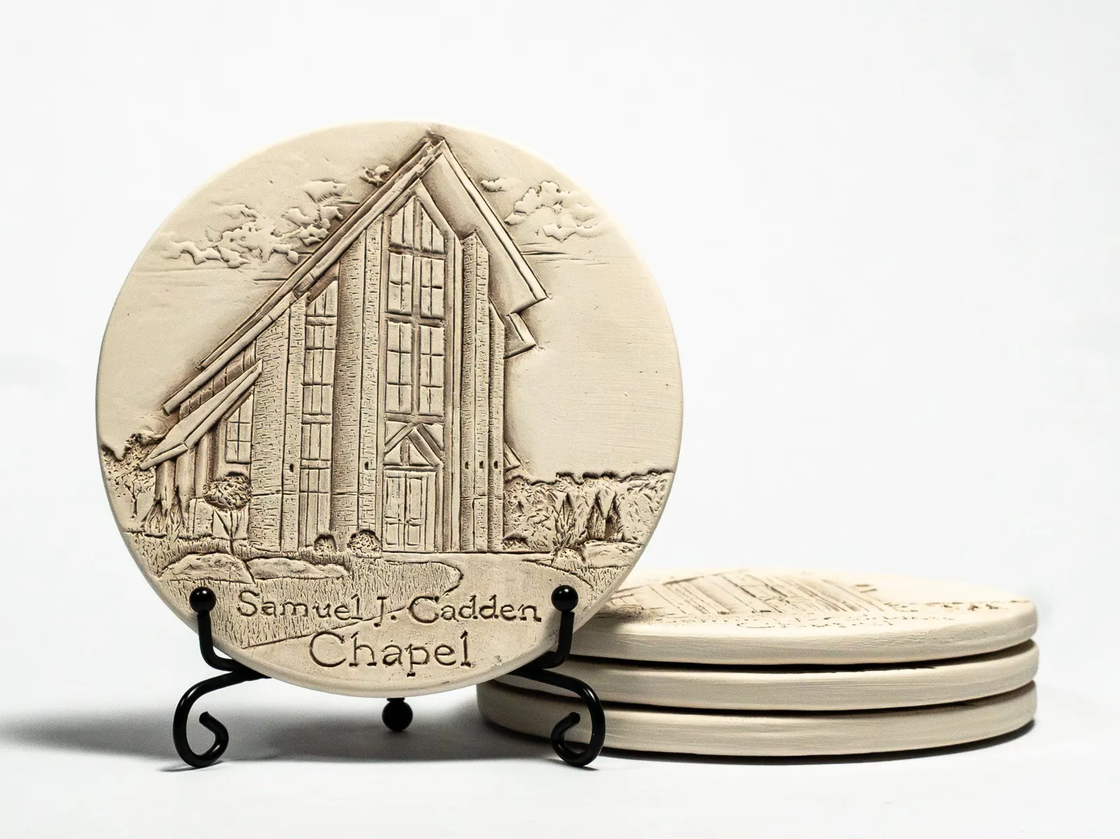 Carved ceramic coasters photographed with directional light revealing the relief and presentation hardware